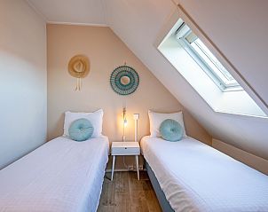 Lichte slaapkamer in De Strandleeuwerik, Texel, met twee eenpersoonsbedden en een prachtig uitzicht door het dakraam.