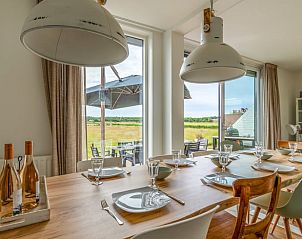 Eetkamer in Huisje in De Koog, Texel, met grote tafel en uitzicht op de natuur van de Waddeneilanden.