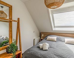 Sfeervolle slaapkamer in Huisje in De Koog, Texel, met dakraam en houten accenten.