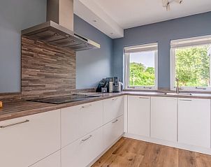 Moderne keuken in Huisje in De Koog, Texel, met uitzicht op de groene omgeving van de Waddeneilanden.