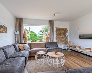 Gezellige zithoek in Huisje in De Koog, Texel, met uitzicht op de groene tuin en de Waddeneilanden.