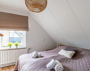 Slaapkamer in Huisje in De Koog, Texel, met grote ramen en natuurlijke lichtinval.