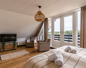 Luxe slaapkamer in Huisje in De Koog, Texel, met balkon en uitzicht op de Waddeneilanden.