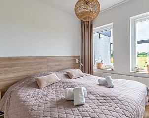 Slaapkamer in Huisje in De Koog, Texel, met uitzicht op de tuin en comfortabele bedden.