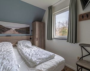 Slaapkamer in vakantiehuis Nieuwlanderweg 77, De Koog Texel met tweepersoonsbed en kunstwerk.