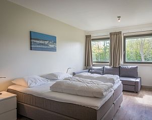 Gerumiges Schlafzimmer in Orchismient 24, Ferienhaus De Koog, Texel mit Doppelbett und Blick auf die Natur.