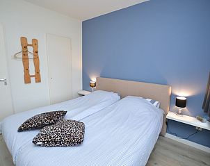 Sfeervolle slaapkamer van Appartement Kerckeland 106, De Koog, Texel met blauw accentmuur en gezellige verlichting.