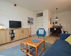 Moderne woonkamer met tv en boekenplank in Appartement Kerckeland 126, Texel.