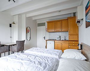 Praktische keuken in Twee persoons studio Texel met houten kasten en compacte eethoek.