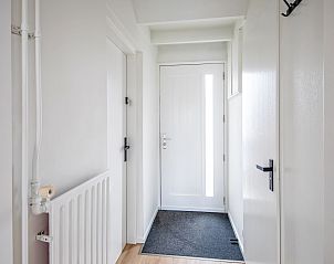 Inkomhal van Twee persoons studio De Koog Texel met strakke witte afwerking en houten vloer.