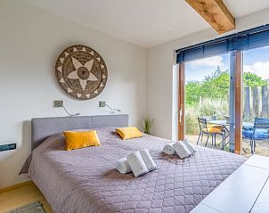 Schlafzimmer im Ferienhaus in De Koog mit bequemem Bett und Zugang zu einer privaten Terrasse auf Texel.