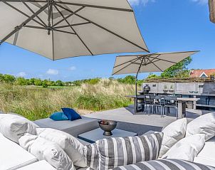 Sonnige Terrasse des Ferienhauses in De Koog mit bequemen Sitzgelegenheiten und Blick auf Texel.