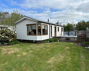 Chaletpark Bregkoog - Bregkoog chalet 214 in De Koog, Texel met groene tuin en houten omheining, ideaal voor een ontspannen vakantie.