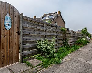 Ingang van Vakantiehuis 2490 in De Koog, Texel met houten poort en groene omgeving.