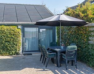 Schaduwrijke zithoek op het terras van Bungalow 1, De Koog, Texel, met comfortabele stoelen.