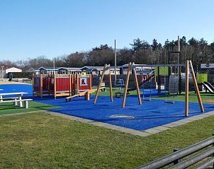 Uitgebreide speeltuin bij Chalet Bregkoog 27, De Koog Texel, met schommels en klimrekken voor kinderen.