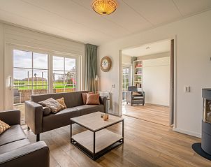 Gezellige woonkamer in De Zandhaas, vakantiehuis in De Koog, Texel, met uitzicht op de tuin en een sfeervolle houtkachel.