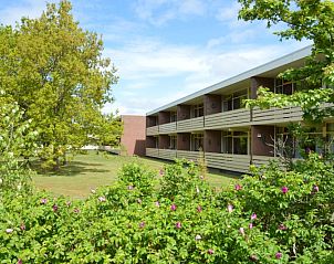 Auenansicht des Appartements Kerckeland 68 in De Koog, Texel, umgeben von Grnflchen und Blumen.
