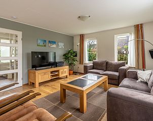 Moderne woonkamer van Vakantiehuis Kamperfoelie 43 met sauna in De Koog, Texel, met flatscreen-tv en houten meubels.