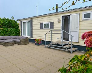 Chalet Bregkoog 138 'Sinne' in De Koog, Texel biedt een ruim terras met loungebank en bloeiende planten.