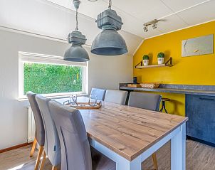 Eetruimte in Vakantiehuis Kamperfoelie 71, De Koog, Texel, met houten tafel en moderne verlichting.