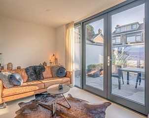 Lichte woonkamer met uitzicht op het terras bij Het Bospad - Brink 15 in De Koog, Texel.