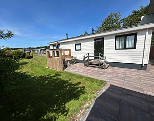 Achtertuin van Chalet Bregkoog 213, De Koog, Texel met ruim terras en grasveld.