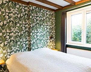 Slaapkamer in De Koperwiek Texel met groene accenten en grote ramen.