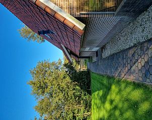 Zijaanzicht van Agter Mienterglop - Vakantiehuis 5103, De Koog, Texel, met tuinpad en groene natuur.