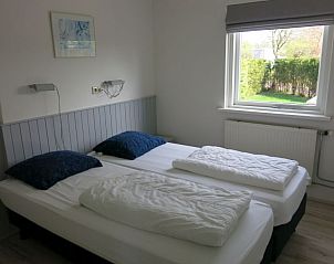 Lichte slaapkamer in Bungalow 35, Texel met uitzicht op de tuin en twee eenpersoonsbedden.