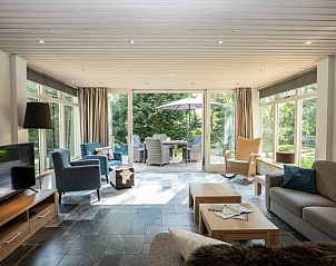 Ruime woonkamer van Westenwind in De Koog, Texel, met grote ramen en toegang tot het terras.