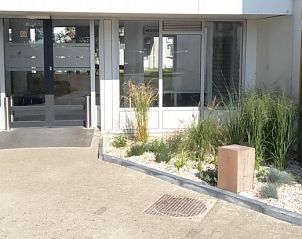 Ingang van De Pelikaan Appartementen, De Koog, Texel, omgeven door groene planten.