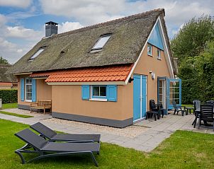 T4A Comfort bungalow met rieten dak in De Koog, Texel, omgeven door groene tuin en terras.