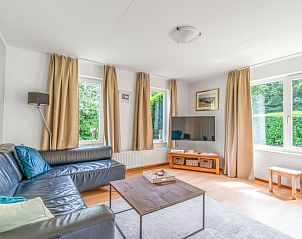 Gezellige woonkamer in Vakantiehuis Kamperfoelie 85, De Koog, Texel met grote ramen en comfortabele zithoek.