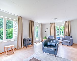 Lichte woonkamer in Vakantiehuis Kamperfoelie 85, De Koog, Texel met toegang tot de tuin en comfortabele stoelen.