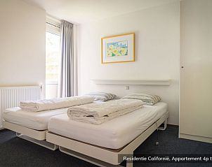 Eethoek in Type 4 vakantiehuis, De Koog Texel, met houten tafel en groene stoelen naast grote ramen.