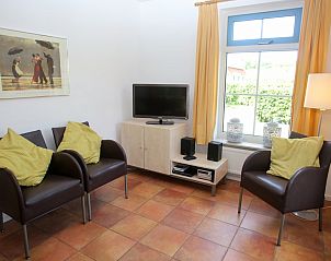 Stijlvolle zithoek in vakantiehuis T8A, De Koog, Texel met moderne stoelen en televisie, ideaal voor een gezellige avond.