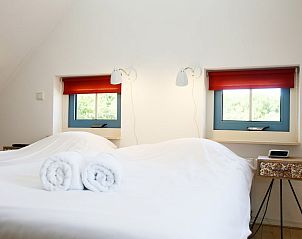 Sfeervolle slaapkamer in T8A bungalow, De Koog, Texel met tweepersoonsbed en uitzicht op de groene omgeving, ideaal voor rust.