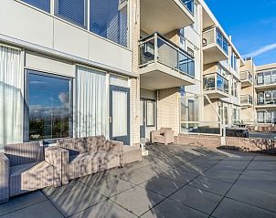 Groot terras bij Appartement Juliana 076 Eilandzicht, De Koog, Texel met comfortabele zitjes en zonlicht.