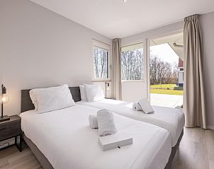 Moderne badkamer in Villa 8, een vakantiehuis in De Koog, Texel met ruim bad en dubbele wastafel, perfect voor ontspanning op de Waddeneilanden.