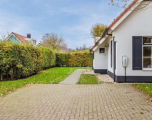 Bungalow T6A in De Koog, Texel, omringd door natuur met een charmant rood dak en ruime tuin voor een ontspannen vakantieverblijf.