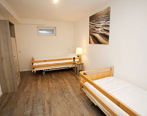 Gezellige slaapkamer in T6AM Comfort bungalow, De Koog, Texel met houten vloeren en schilderij, ideale vakantieaccommodatie op de Waddeneilanden.
