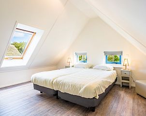 Gezellige slaapkamer in T6AM Comfort bungalow, De Koog, Texel. Helder interieur met dakraam en comfortabele bedden voor een ontspannen verblijf.