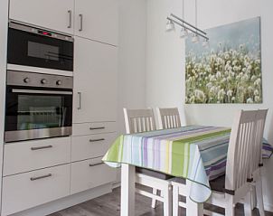 Eetruimte in 't Kerckeland - Appartement Kerckeland 92 in De Koog, Texel met kleurrijk tafelkleed en moderne keukenapparatuur.