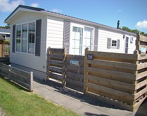 Chalet Bregkoog 255 in De Koog, Texel met houten omheining en zonnige buitenkant.