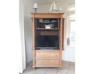 Houten kast met tv en boeken in vakantiehuis Pauwenhof Texel, De Koog.