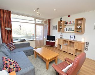 Moderne woonkamer van Appartement Kerckeland 50, De Koog, Texel met uitnodigende zithoek en boekenplanken.