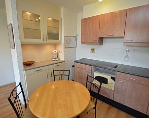 Stijlvolle keuken in Appartement Kerckeland 50, De Koog, Texel met houten kastjes en ronde eettafel.
