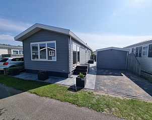 Buitenkant van Chaletpark Bregkoog - Chalet 240 De Texelse Berg, De Koog, Texel met modern terras en parkeerplaats.