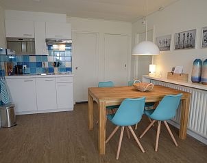 Stylish dining area in Grand Hotel Opduin - Holiday Apartment A, De Koog, Texel, with wooden table and colorful chairs.